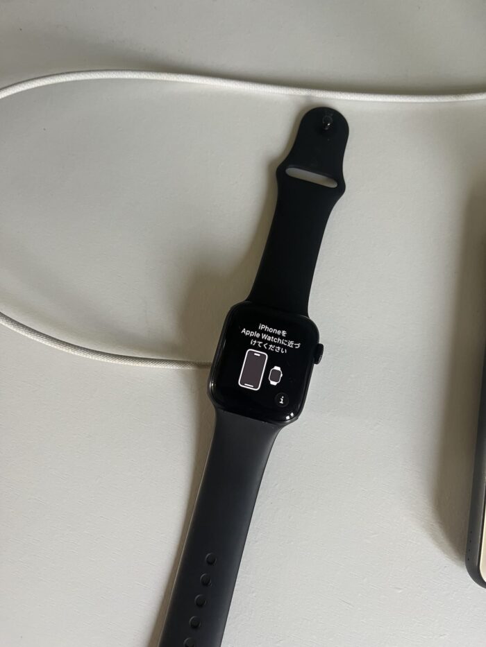 Apple Watch SE met setup-scherm dat vraagt om iPhone te koppelen, liggend aan de magnetische oplader